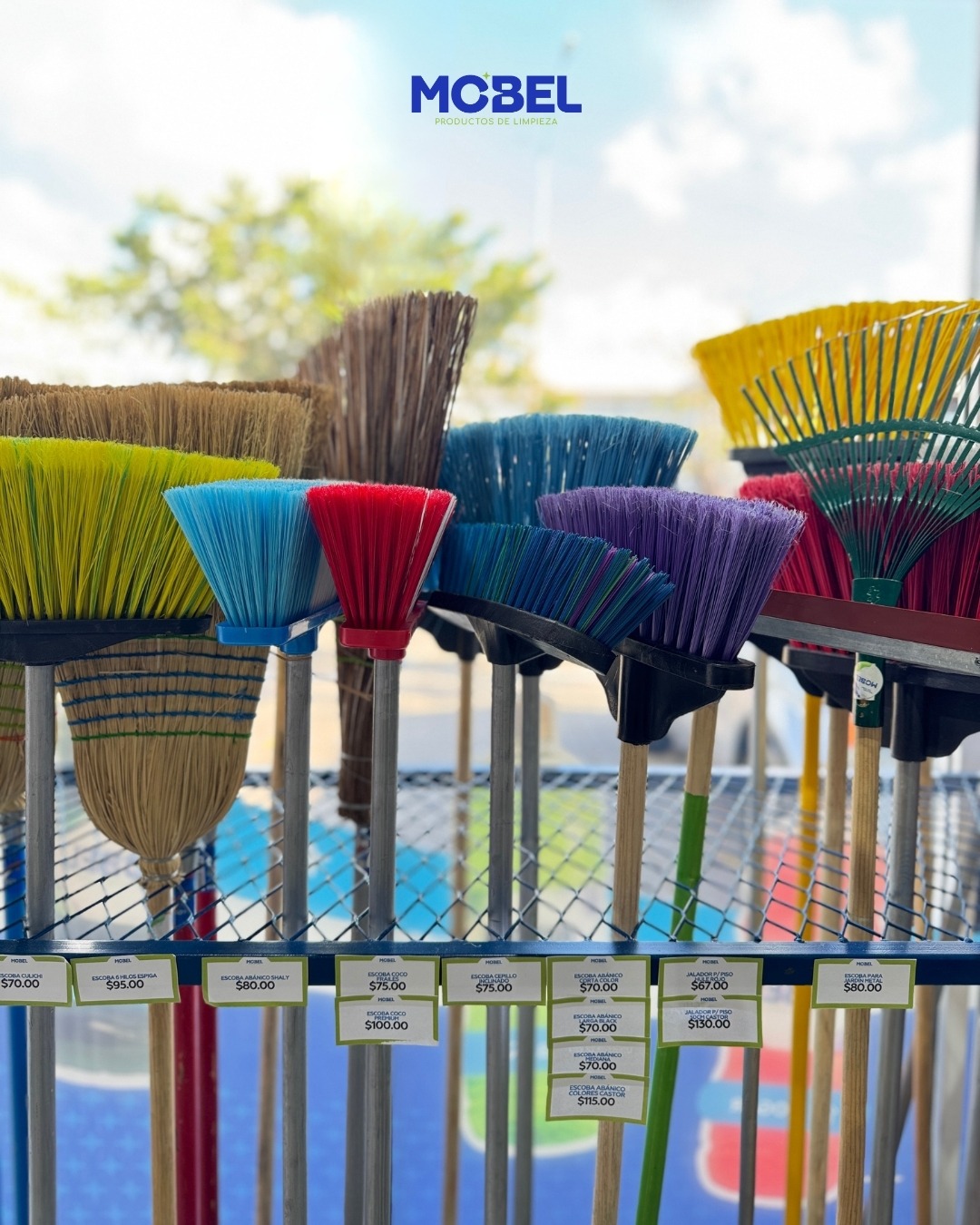 Exhibición de escobas de distintos colores en la tienda MOBEL